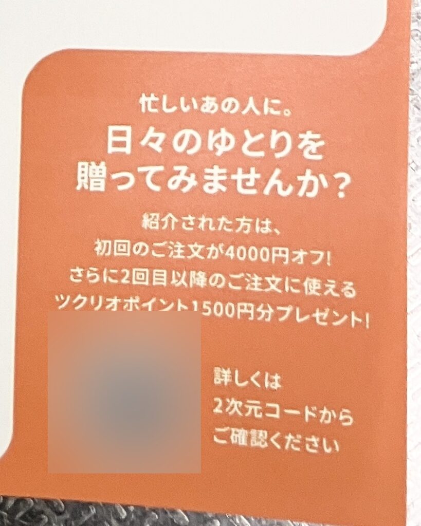 配送箱に同梱される献立表の裏に印刷された友達紹介の案内（QRコード部分はぼかし加工）